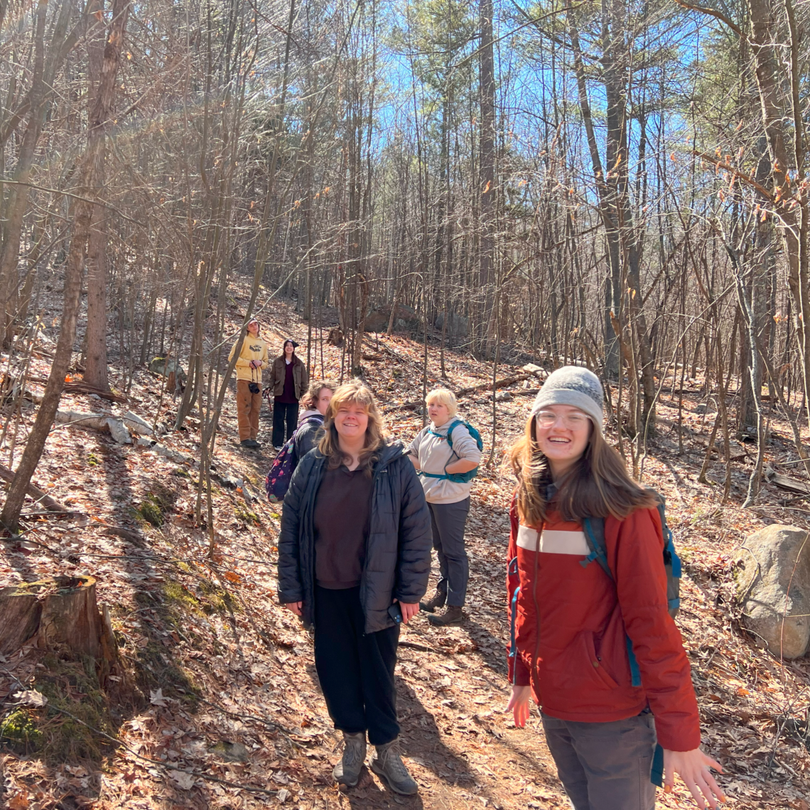 A group of students on a forested trail that leads up.