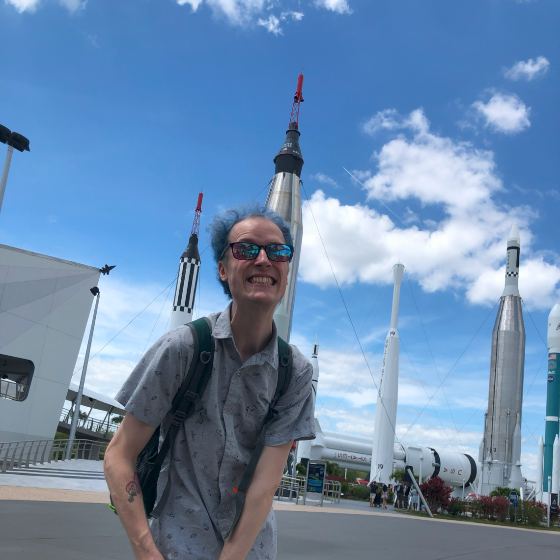 Phoenix standing in front of a series of rockets at Kennedy Space Center