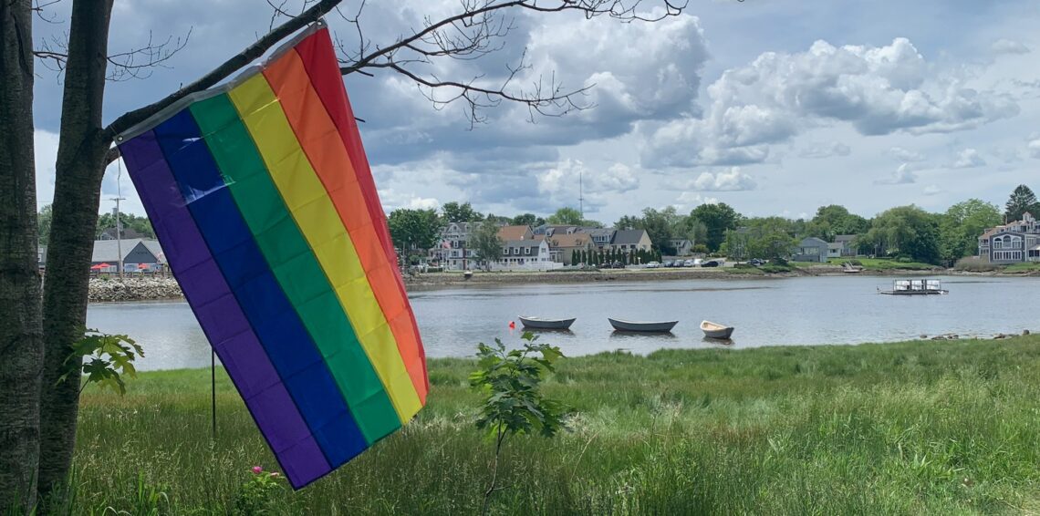 A Pride flag with the Kennebunk River in the background.