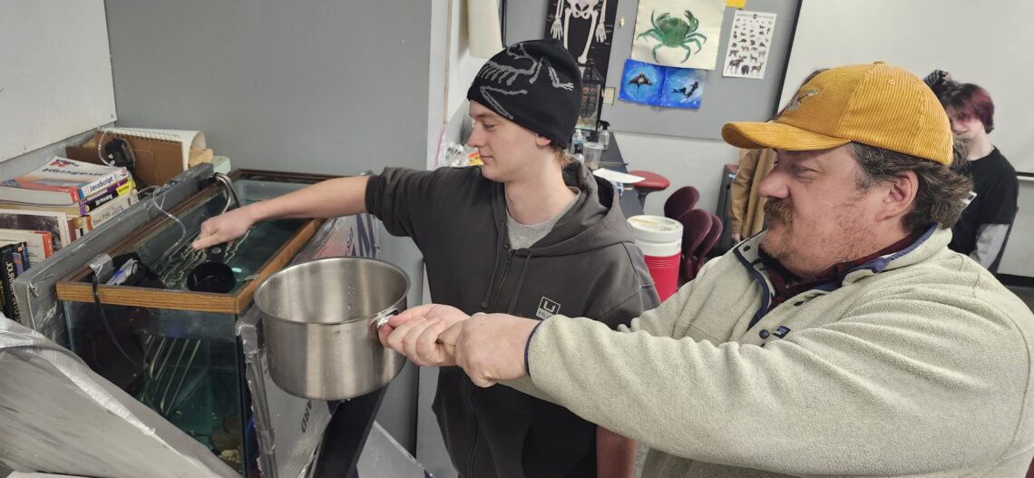 A student and our head of school prep the aquarium.
